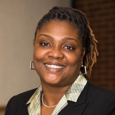 Smiling woman with braided hair in professional attire.