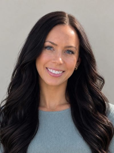 Smiling woman with long dark hair wearing a blue sweater.