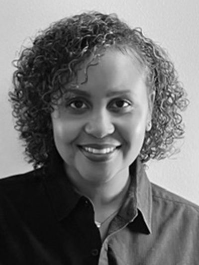Black and white portrait of a smiling woman with curly hair.