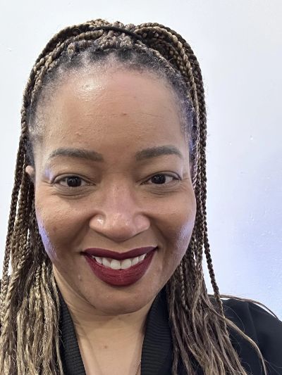 Smiling woman with braided hair and dark lipstick.