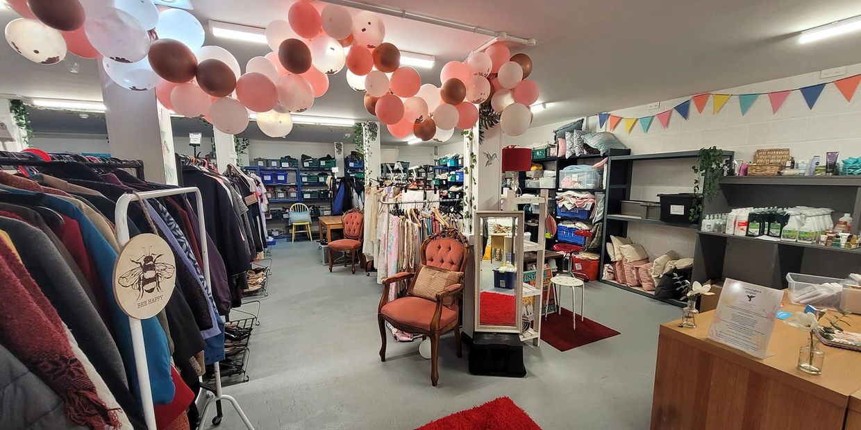 Cozy thrift shop with balloons, clothes racks, and cozy seating.