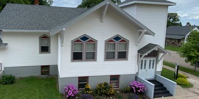White church building with colorful flower beds outside.