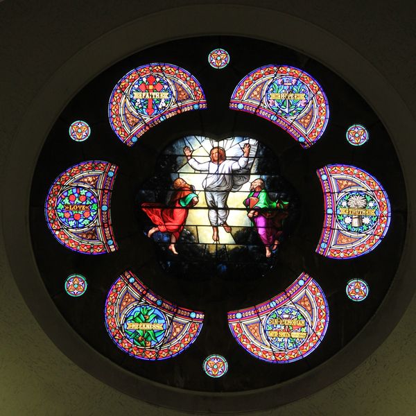 A circular stained glass window depicting a religious scene with seven virtues.