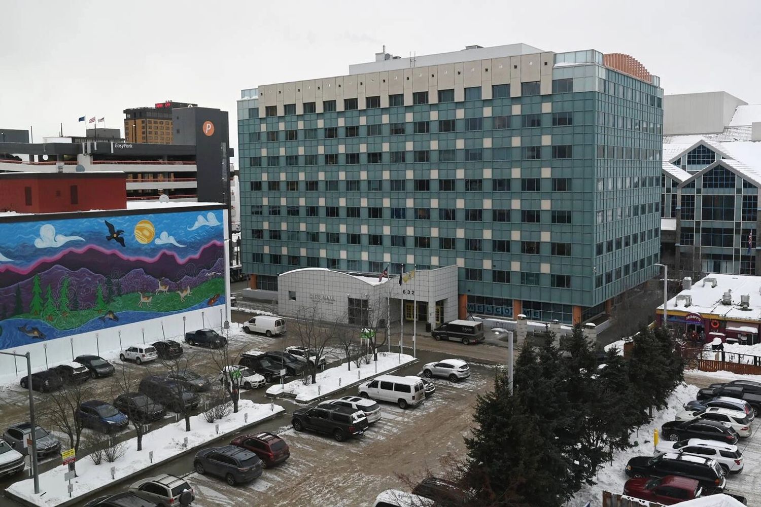 Snow-covered cityscape with a mural and a large building labeled City Hall.