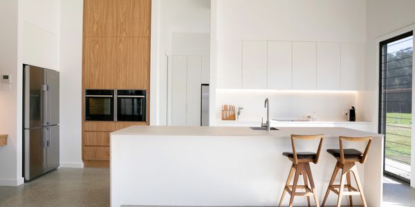 Minimalist modern kitchen with white cabinetry and wooden accents.