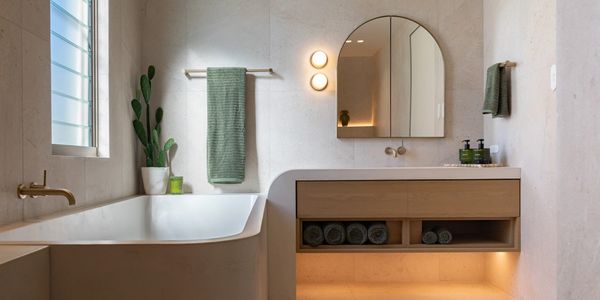 Modern bathroom with a bathtub, round mirror, and green towels.
