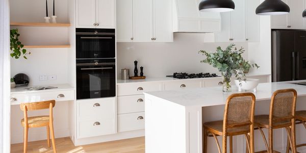 Bright modern white kitchen with wooden accents and a marble island.