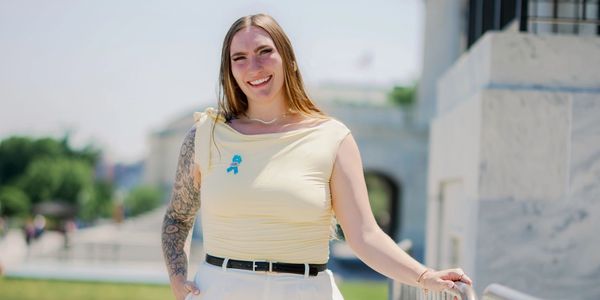 Smiling woman with tattoos outdoors on a sunny day.