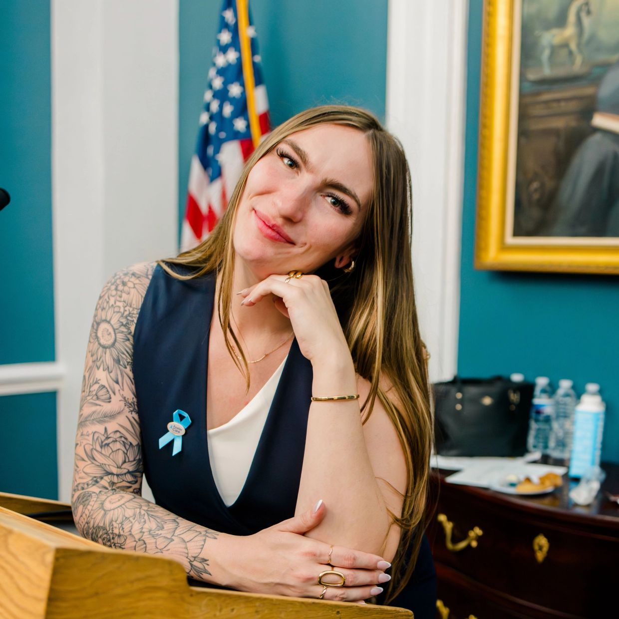 Smiling woman with tattooed arm in formal setting.