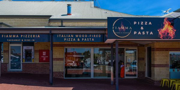 Fiamma Pizzeria storefront with clear blue sky and signage.