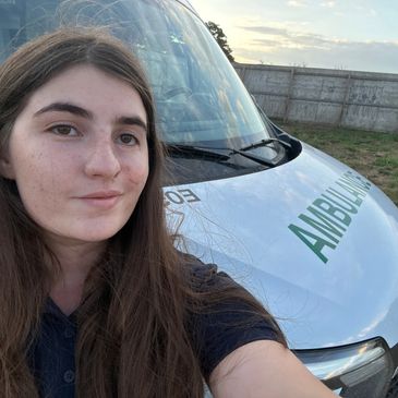 Young woman takes a selfie in front of an ambulance.