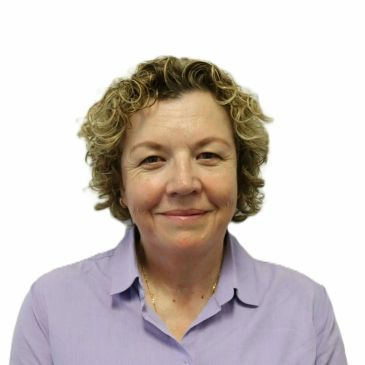 Smiling woman with curly hair wearing a light purple shirt.