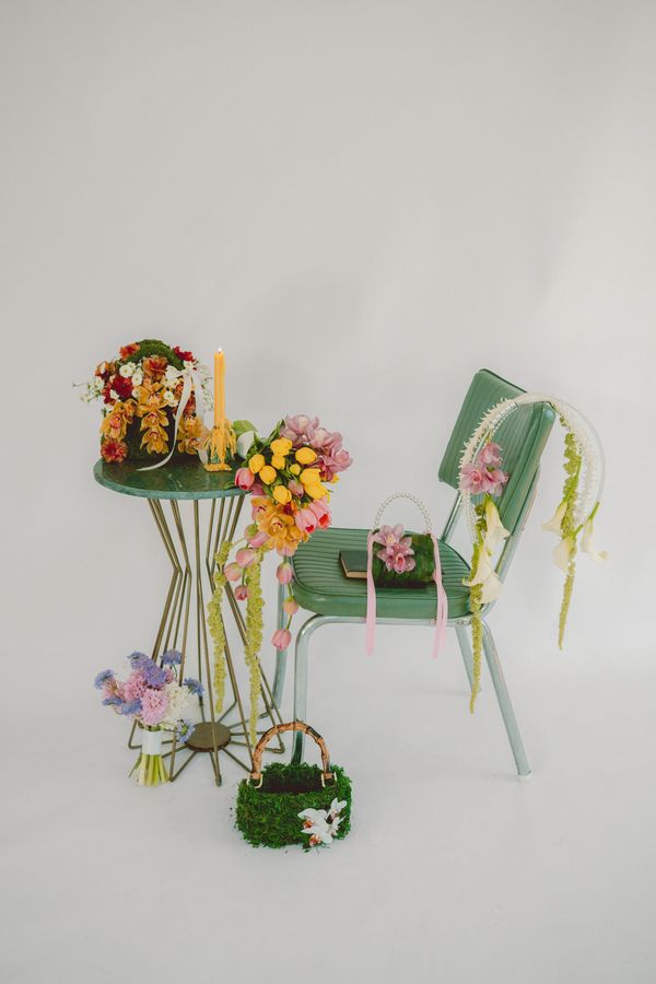 Green chair and table adorned with colorful floral arrangements and a candle.