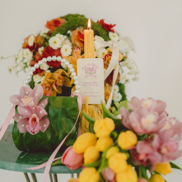 Elegant floral arrangements with a lit candle on a green table.