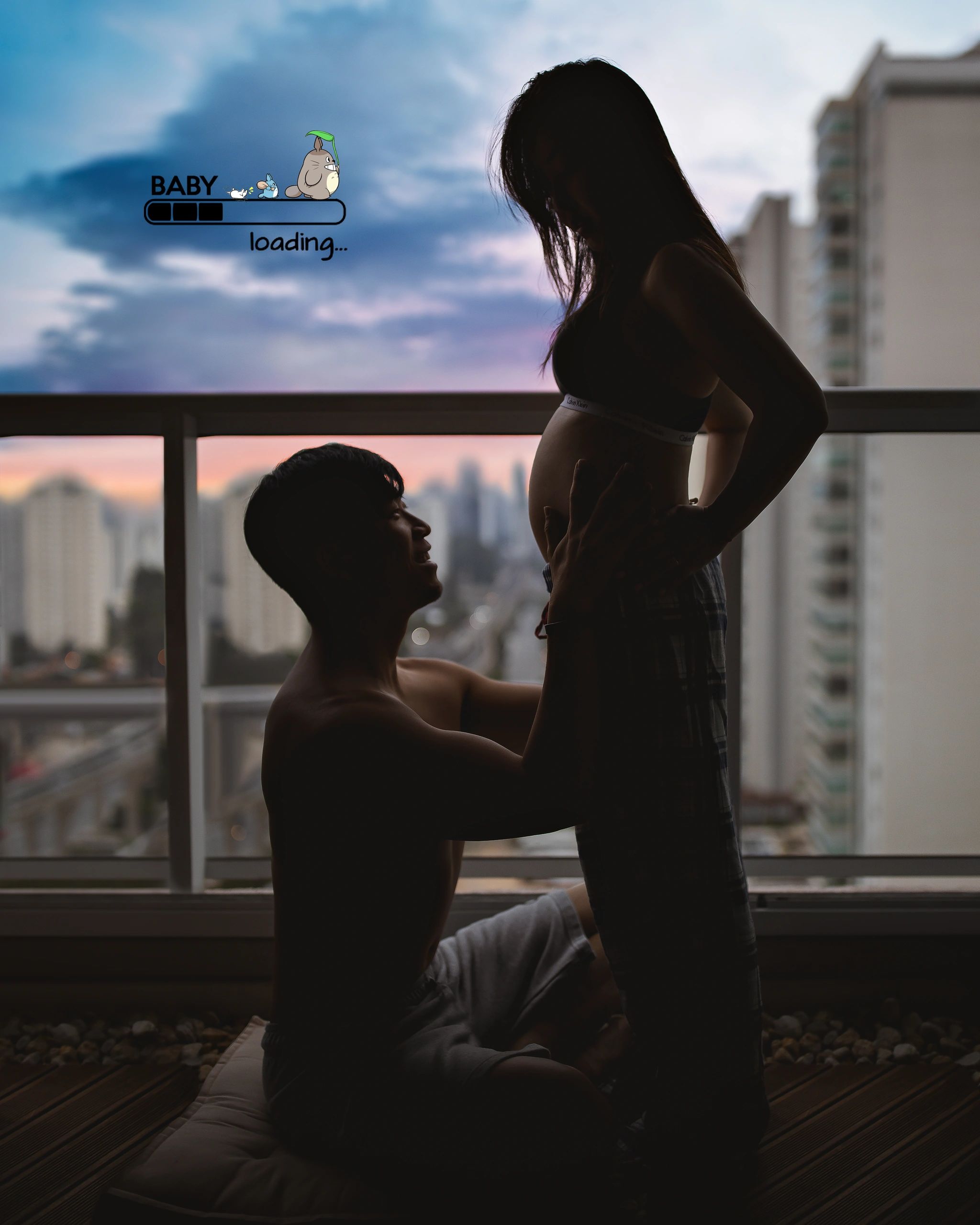 Silhouette of a couple celebrating pregnancy with a loading baby graphic.