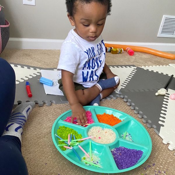 Birthday themed sensory activity with colored rice and a party serving tray and candles.