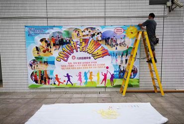A man installs a colorful 2010 summer event banner on a tiled wall.