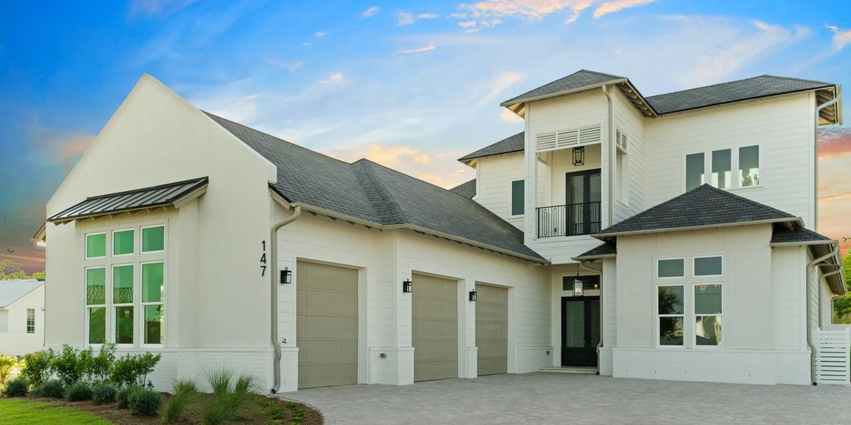 Modern white two-story house with three-car garage and large windows.