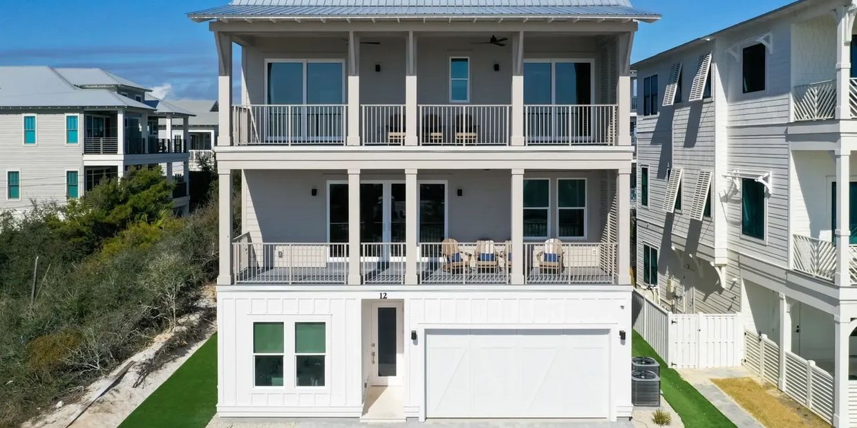 Modern three-story beach house with balconies and a white exterior.