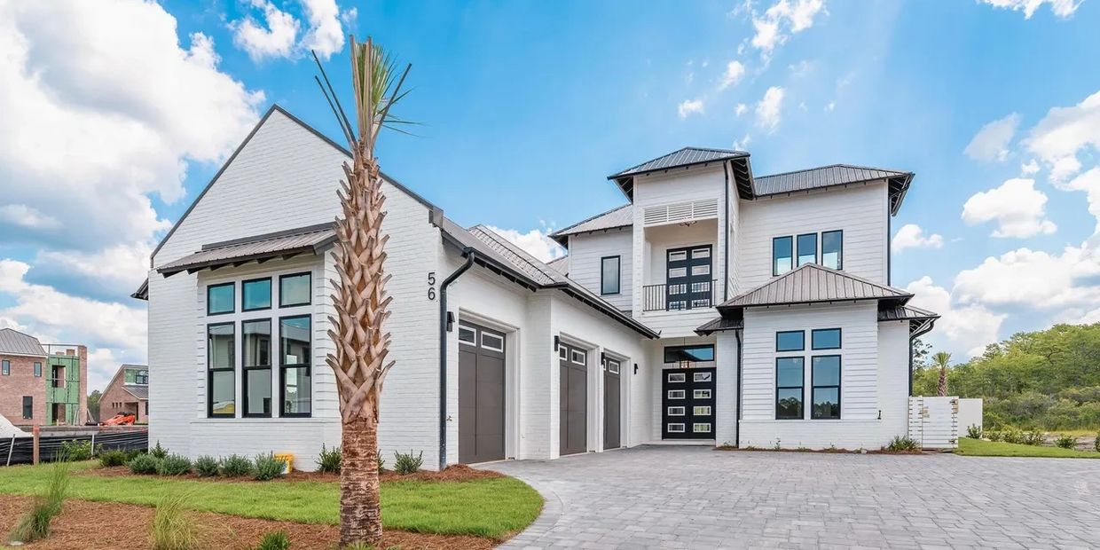 Modern white two-story house with large windows and a three-car garage.