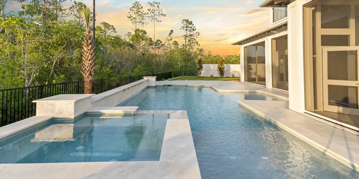 Luxurious backyard pool with a spa and scenic sunset view.