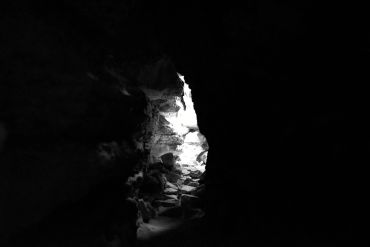 Light shines through a cave opening in darkness.