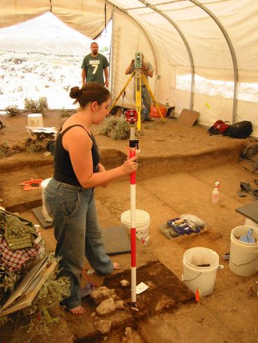 Woman conducting an archaeological excavation inside a tent.