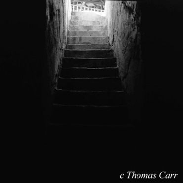 Dark stone staircase leading upward to a bright exit.