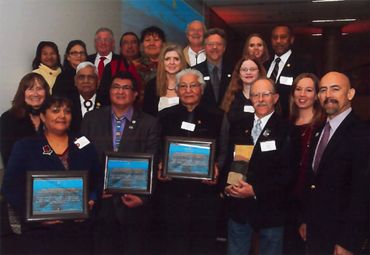 Group photo of people at an award ceremony holding framed certificates.
