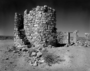 Ruined stone structure with spiral stairs in a desert.