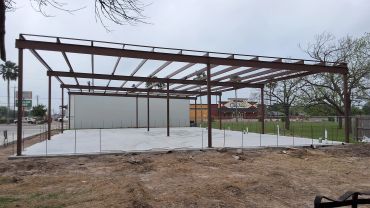 Steel frame structure on a concrete foundation at a construction site.