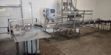 Filling line is filling sanitizers.  Bottle feed turntable and bottom fill gravity filling machine
