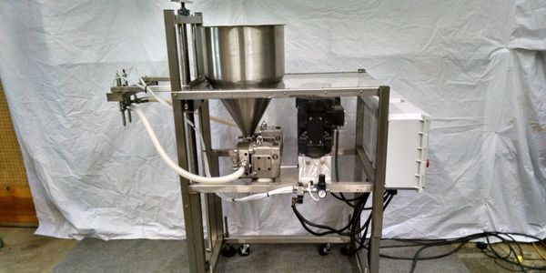 Sanitary 2 head pump filling machine set up to fill sauce into bottles.  The machine is adjustable a