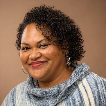 Smiling woman with curly hair wearing a striped sweater.