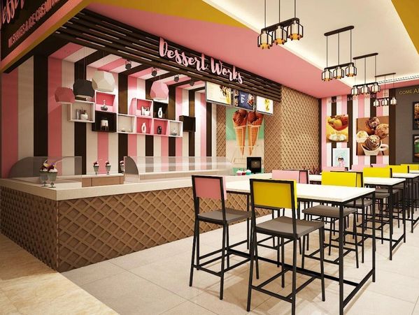 Bright and colorful dessert cafe with pink, yellow, and brown decor and high tables.