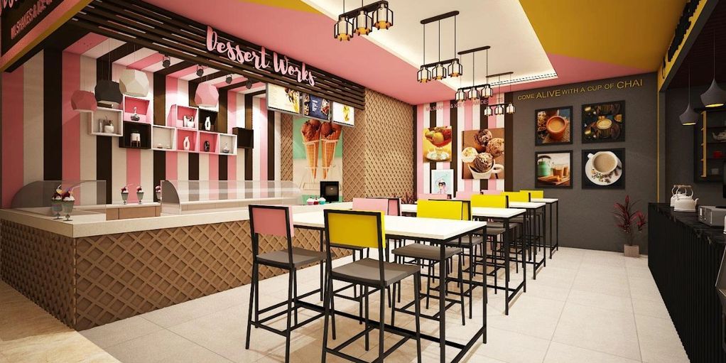 Bright and colorful dessert cafe with pink, yellow, and brown decor and high tables.