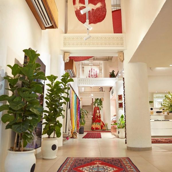 Bright interior of a boutique with plants, carpets, and hanging art.