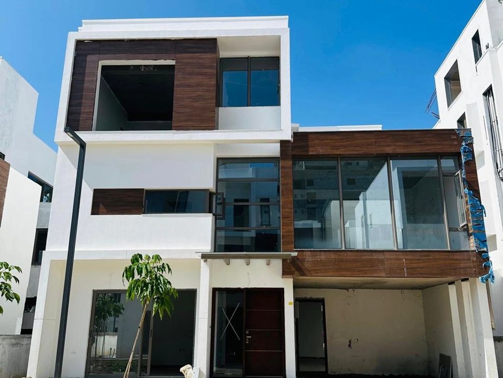 Modern three-story house with clean lines and wood panel accents under a clear blue sky.
