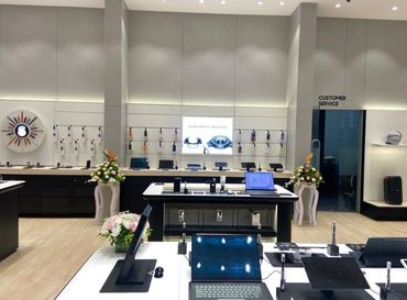 Modern tech store with laptops, smartwatches, and customer service area.