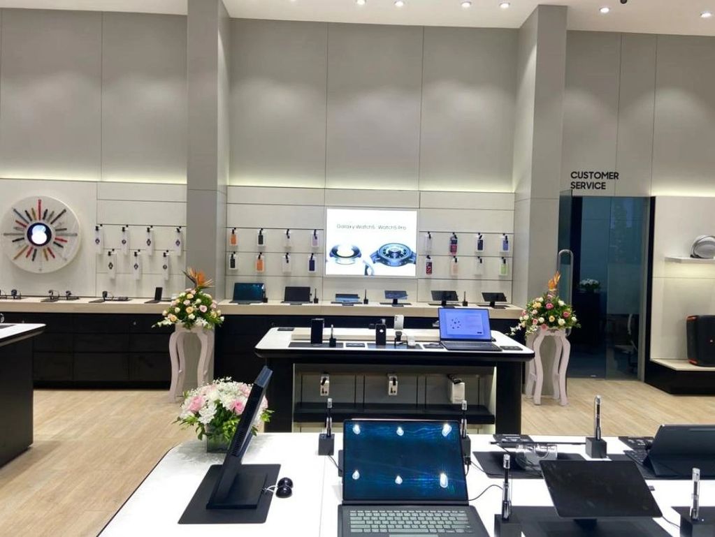 Modern tech store with laptops, smartwatches, and customer service area.