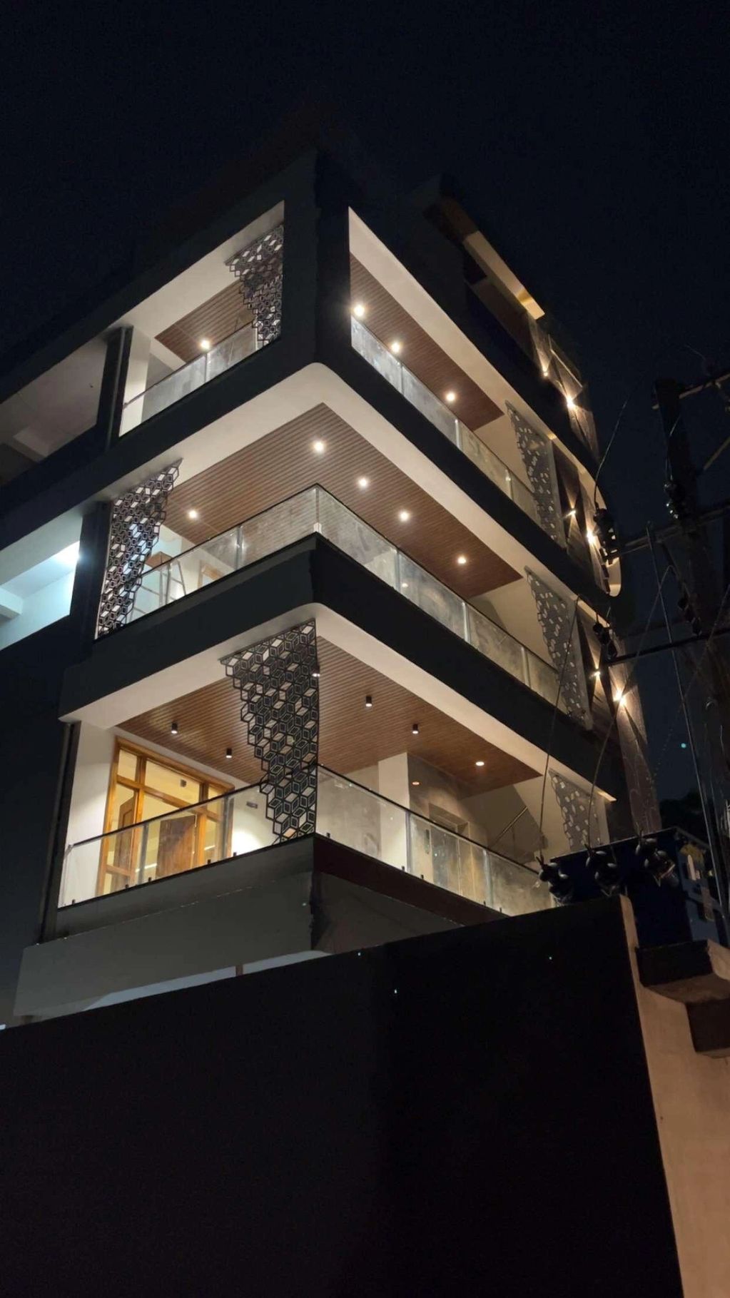 Modern multi-story building with illuminated balconies at night.