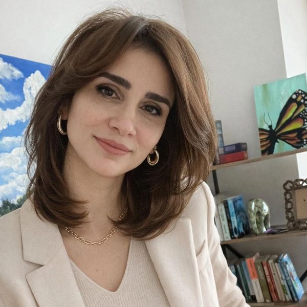 Gülümseyen kadın, kitaplık önünde portre.