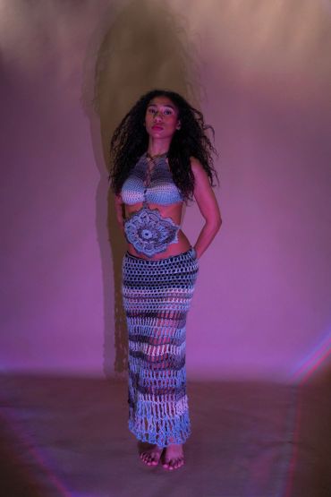 Woman in a crochet outfit with dramatic lighting and shadows.