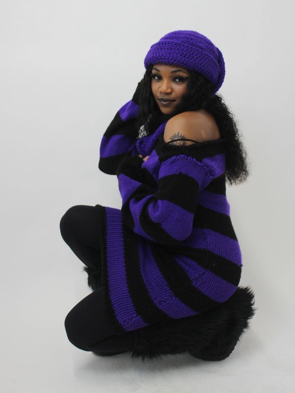 Woman wearing a purple and black striped sweater and matching hat.