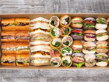 A variety of neatly arranged sandwiches and wraps in a box.