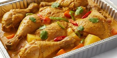 Tray of chicken curry with vegetables and herbs.