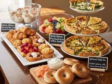 Assorted breakfast spread including quiches, pastries, fruit, bagels, and smoked salmon.
