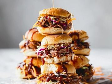 Stack of pulled pork sandwiches with barbecue sauce and coleslaw.