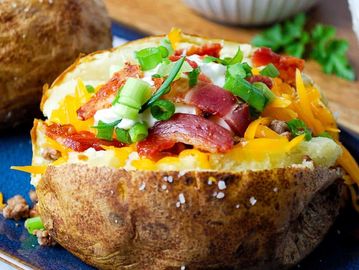 Loaded baked potato with bacon, cheese, sour cream, and green onions.