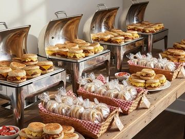 Breakfast sandwiches and wrapped muffins arranged on a buffet table.